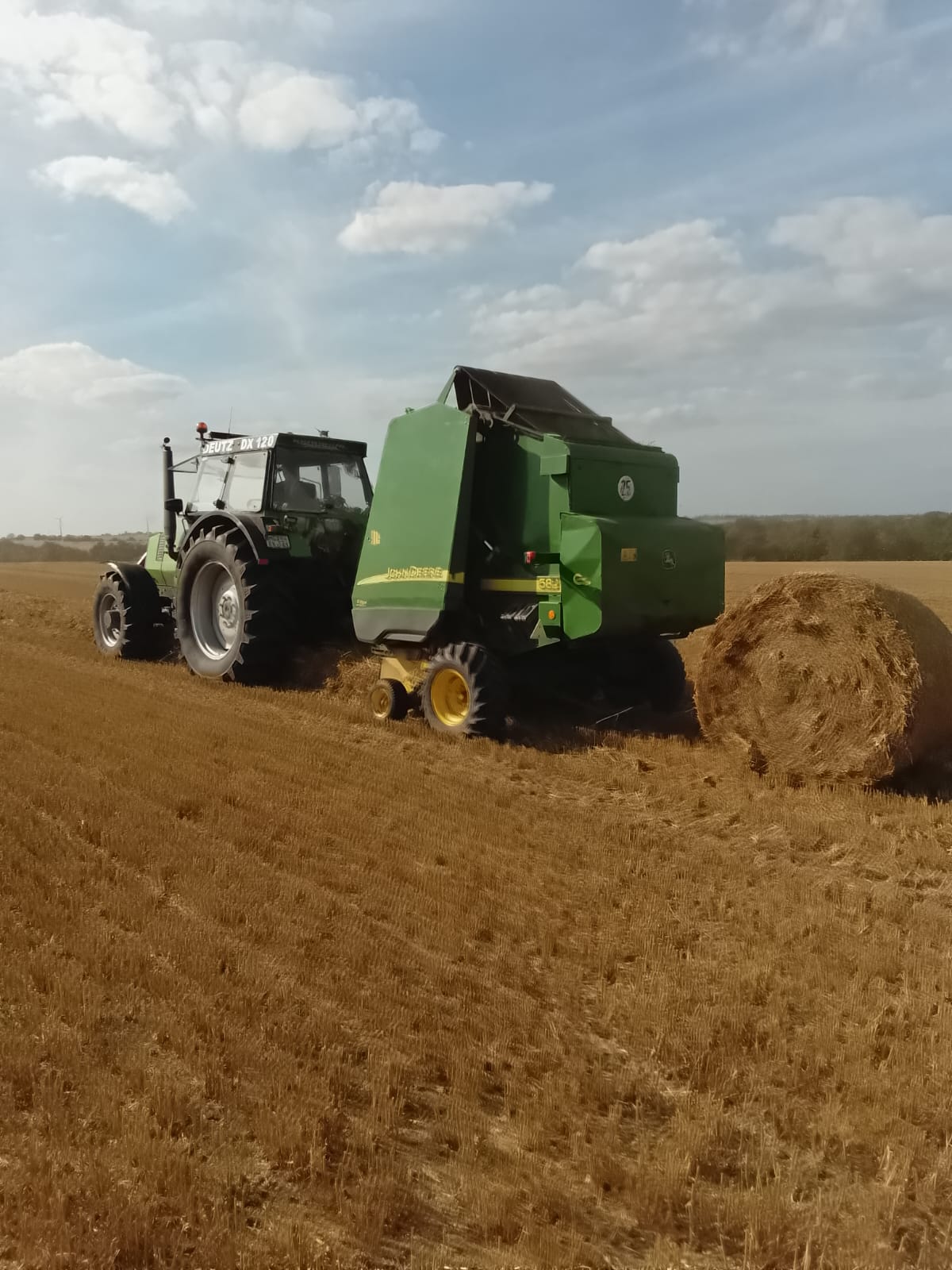 Deutz-Traktor mit Rundballenpresse bei der Strohernte